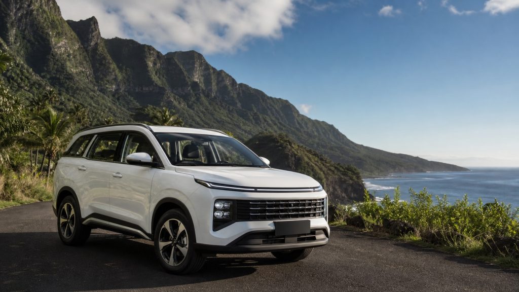 SUV familial blanc 7 places stationné sur une route côtière avec montagnes tropicales et océan à La Réunion