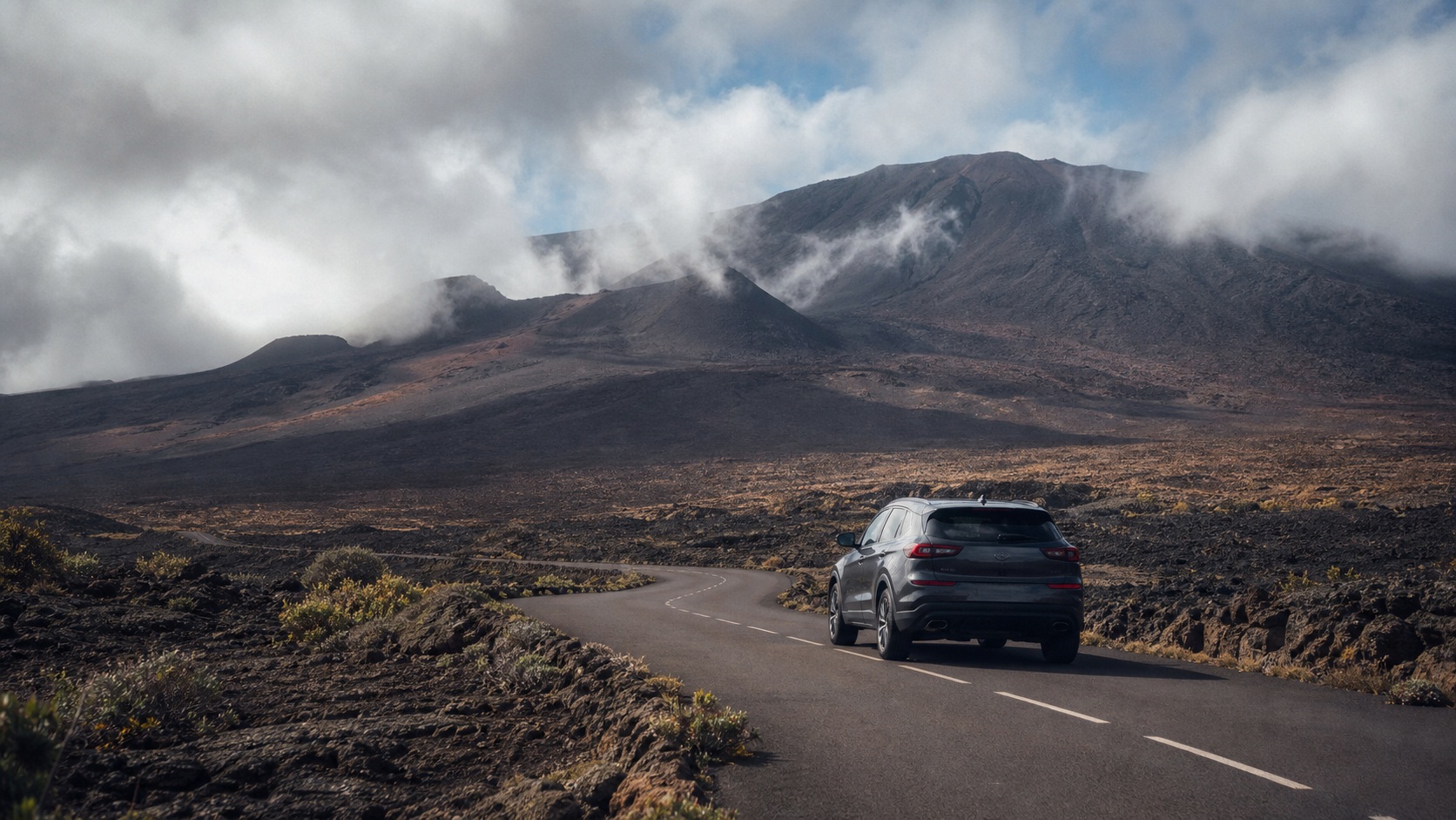 SUV gris roulant sur la Route du Volcan à La Réunion, au cœur des paysages minéraux de la Plaine des Sables près du Piton de la Fournaise
